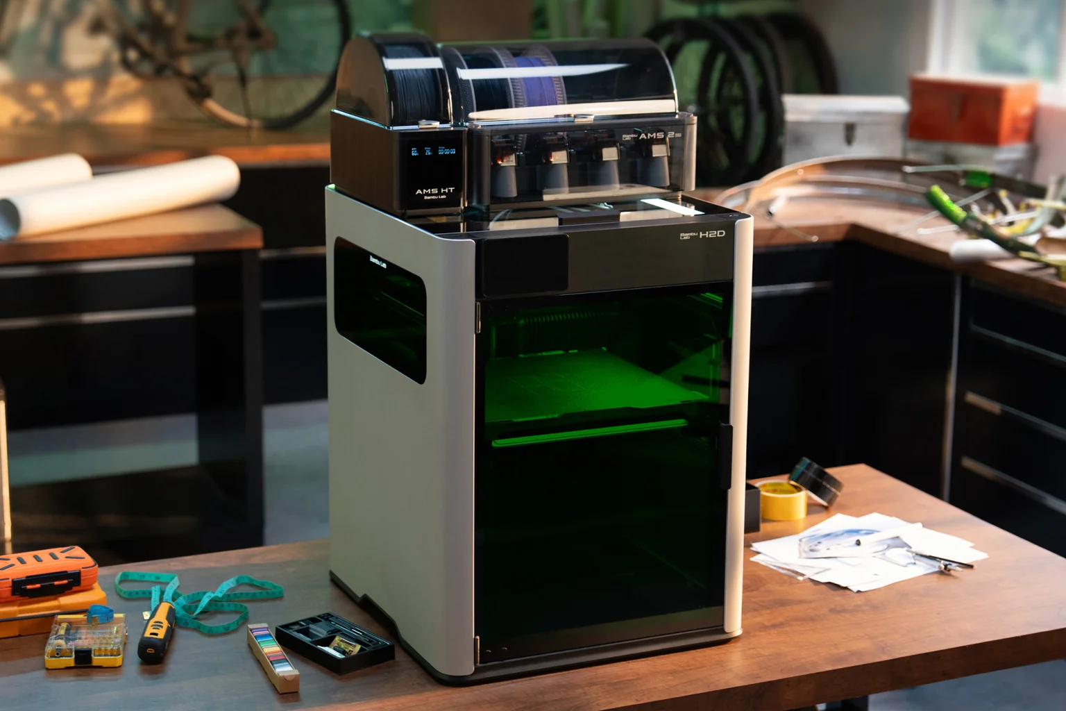 Bambu Lab H2D with the AMS HT on a timber workbench in a fabrication workshop