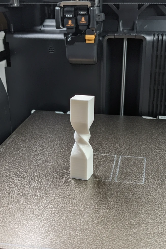 White twisted trophy on the textured build plate inside a 3D printer