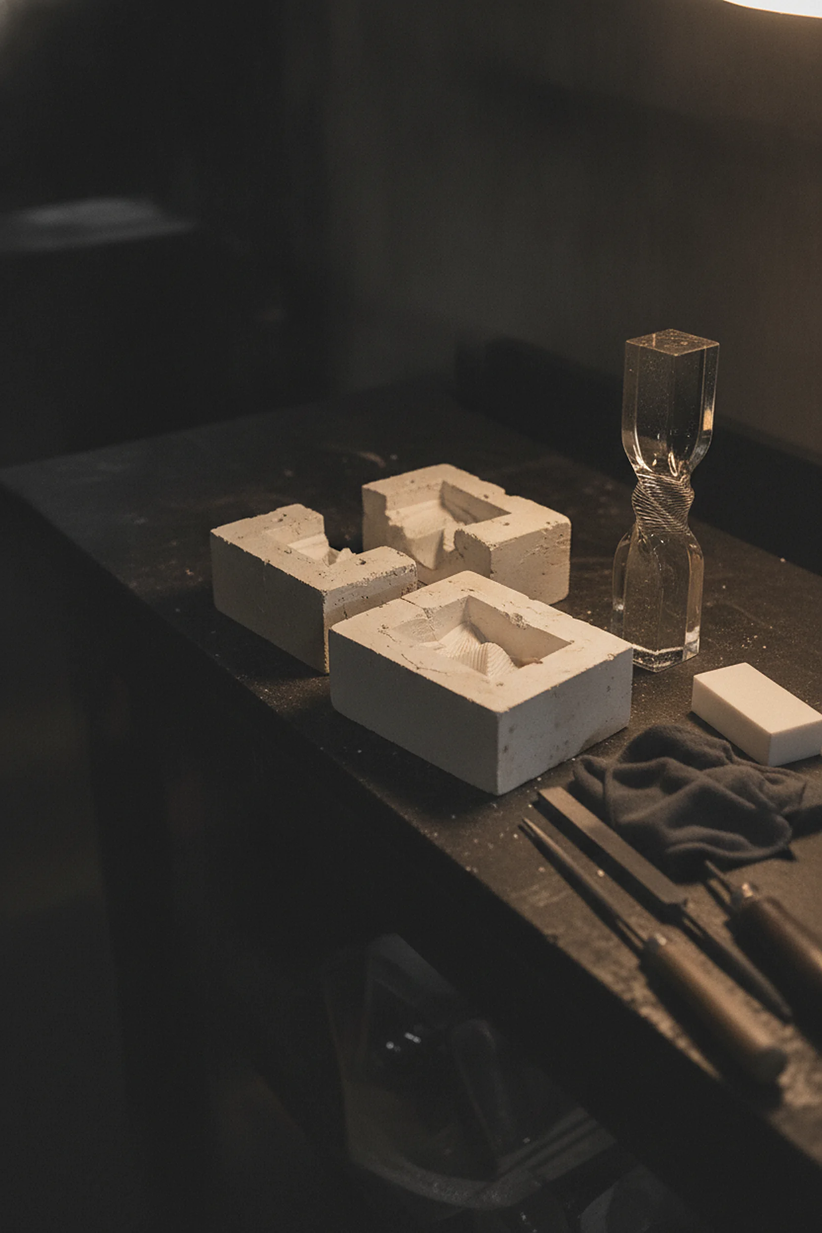Foundry bench with the cast glass trophy, its ceramic mould halves and finishing tools