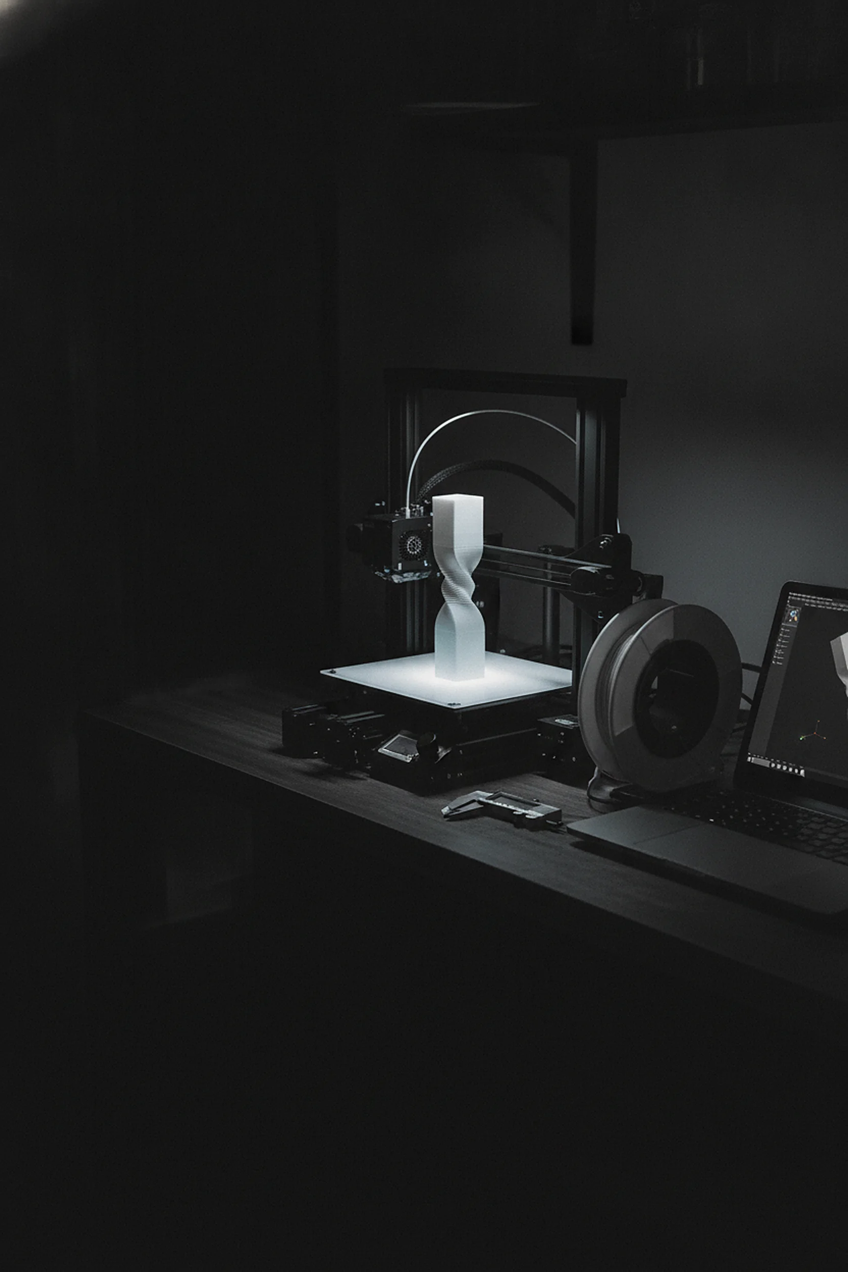 3D printer mid-print with the twisted trophy pattern glowing on the build plate