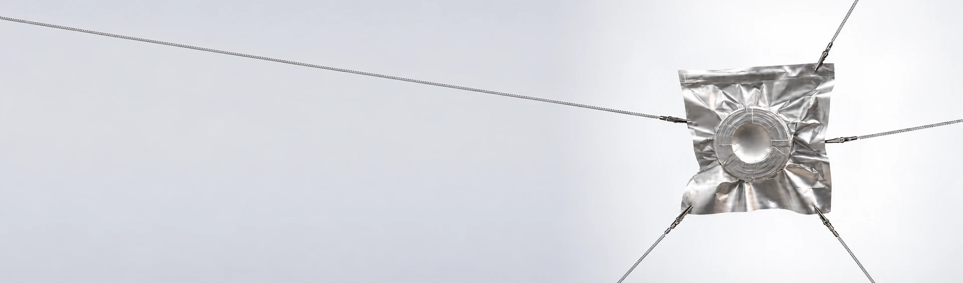 Silver vacuum-sealed filament bag suspended by metal clips and wires
